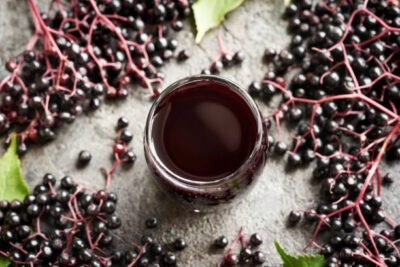 A glass of homemade black elderberry syrup on a table, top view