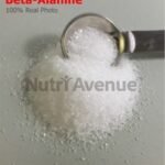A pile of white crystalline Beta-Alanine powder with a metal measuring spoon.